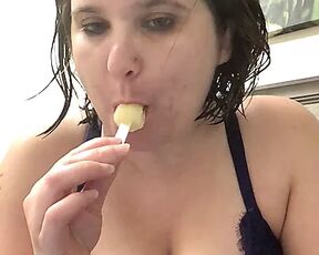 Bored mom with banana popsicle sucking on it